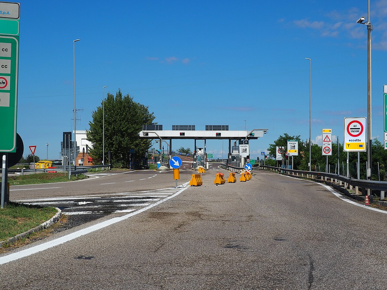 Mautstation einer italienischen Autobahn mit Schildern und Schrankenspuren unter blauem Himmel